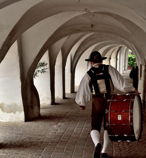 Uomo che cammina sotto i portici a Egna